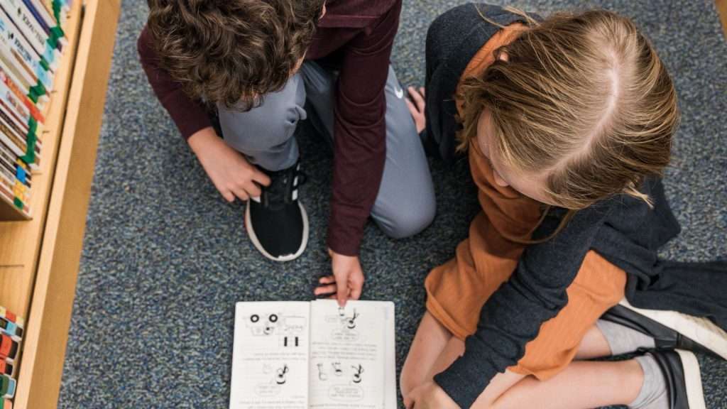 students reading book on floor