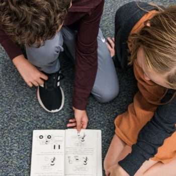 students reading book on floor